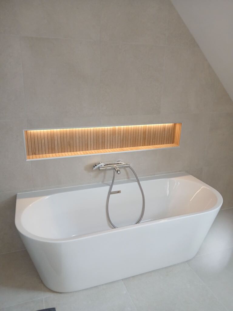 Baignoire design avec éclairage LED encastré au mur dans une salle de bain rénovée.